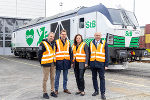 Gruppe von vier Personen mit Warnwesten vor einer grünen Lokomotive mit dem Aufdruck „Steiermark“.