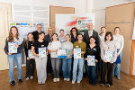 Gruppe junger Menschen mit Zertifikaten bei einer Veranstaltung. Im Hintergrund ein Banner mit dem Logo der Landesregierung Steiermark.