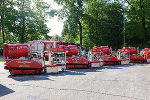 Mehrere Feuerwehranhänger stehen auf einer Fläche, im Hintergrund Bäume.