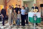 Bildbeschreibung: Gruppe von Menschen vor einem Tisch mit dem steirischen Wappen. Festlicher Rahmen.