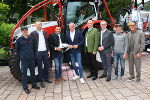 Bildbeschreibung: Acht Männer stehen vor einem Traktor.