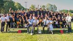 Gruppe in Uniform posiert mit Pokalen im Freien, wahrscheinlich nach einem Wettbewerb.