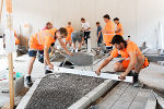 Bildbeschreibung: Zwei junge Männer arbeiten an einem Modell einer Straßenbaustelle.
