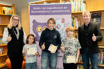 Zwei Erwachsene und drei Kinder vor einem Banner.